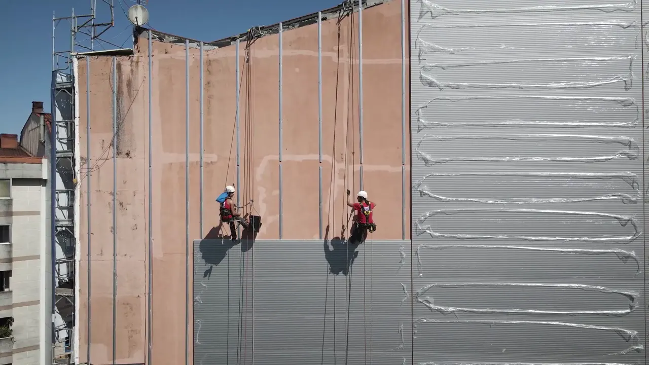 Two rope-access workers on the face of a building under construction.