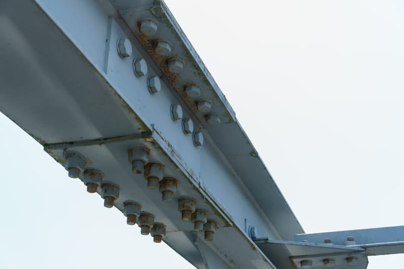 A bolted steel plate girder seen from below along its span.